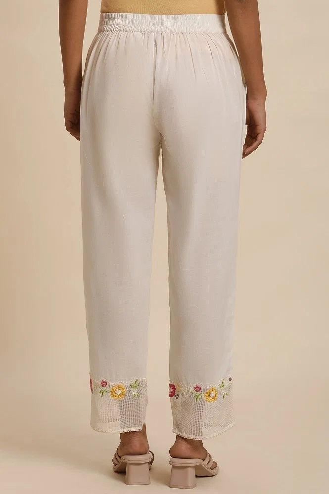 White cotton pants with embroidered detailing at hem by Free Living